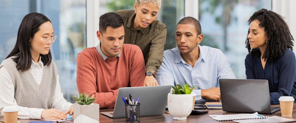 Several trade show employees reviewing information on a laptop.