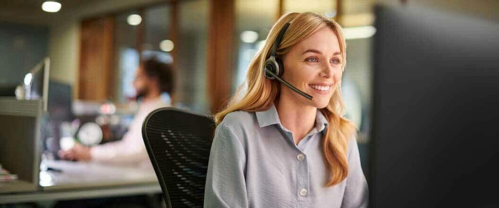 A customer service agent seated at her desk wearing a headset.