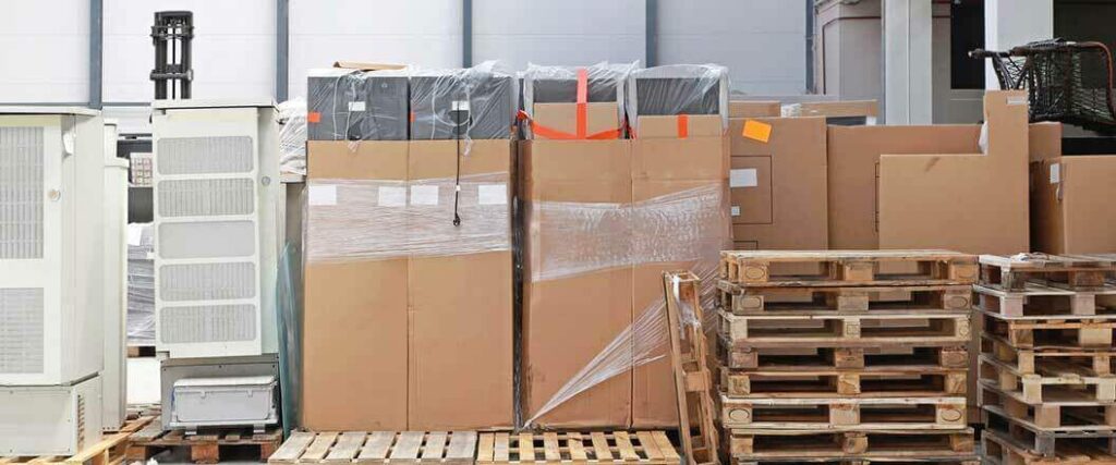 Boxes of trade show display materials stacked on pallets with a forklift in the background.